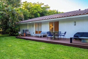 Ein Haus mit Terrasse, Sitzgelegenheiten im Freien und einem Rasen.