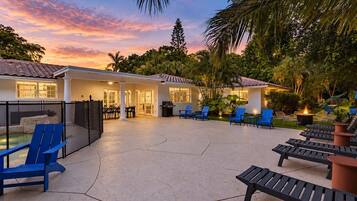 A resort with a pool, outdoor seating, and a sunset view.