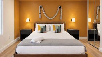 A hotel room with a bed, two bedside tables, a mirror, and a wall-mounted light fixture.