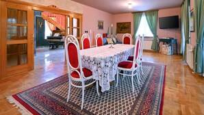 Comedor con una mesa dispuesta para seis personas, rodeada de sillas con cojines rojos, una alfombra estampada y piso de madera.