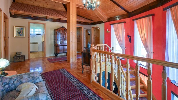Un amplio salón con techo de madera, una escalera y vistas al exterior.