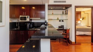 Una cocina moderna con armarios de madera oscura, un microondas integrado y una isla de vidrio con estufa.