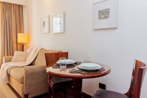 Ein Hotelzimmer mit Esstisch für zwei Personen, einer Couch und einer Lampe.