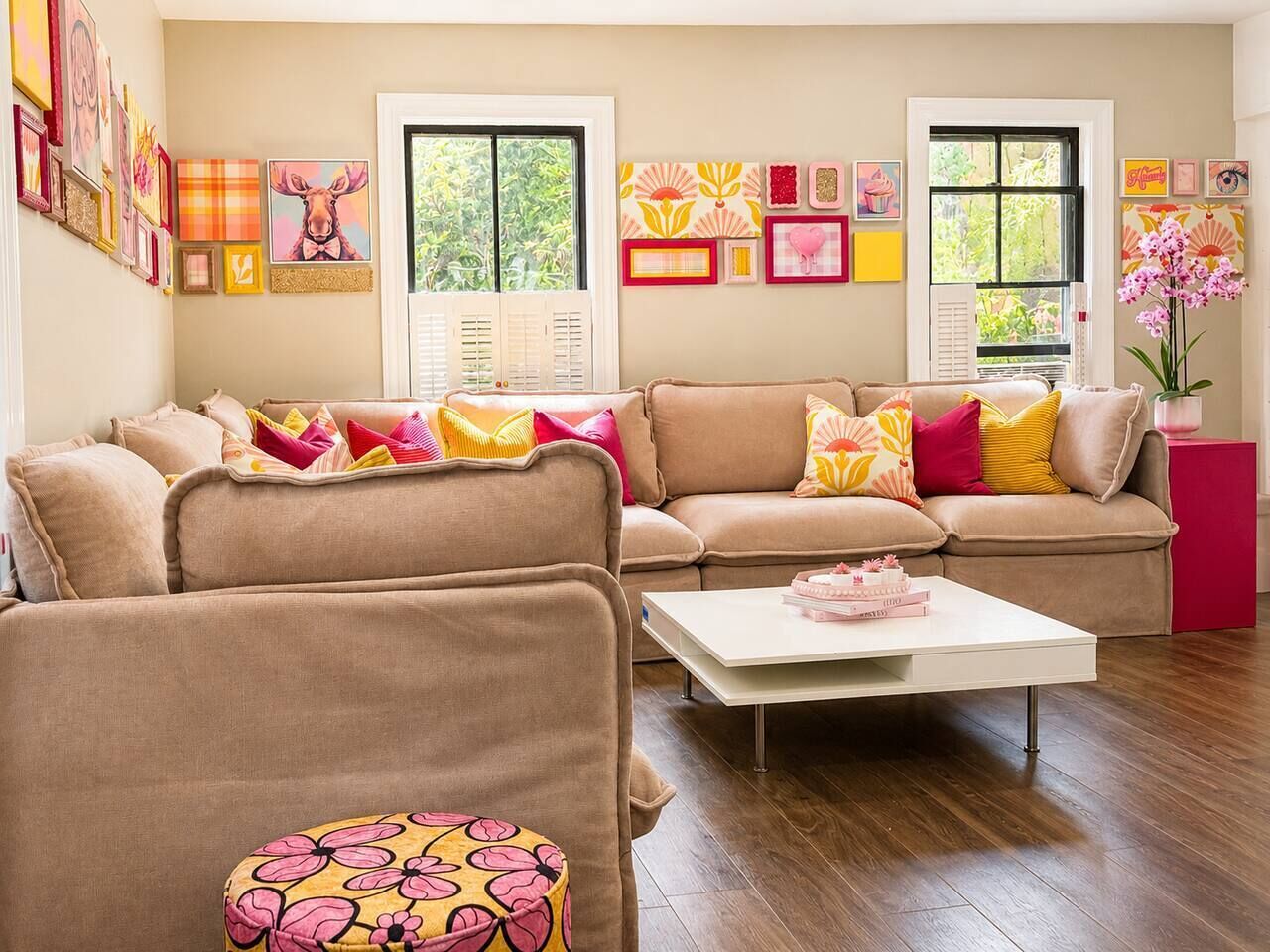 A living room with a beige sofa, a white coffee table, and a patterned ottoman.