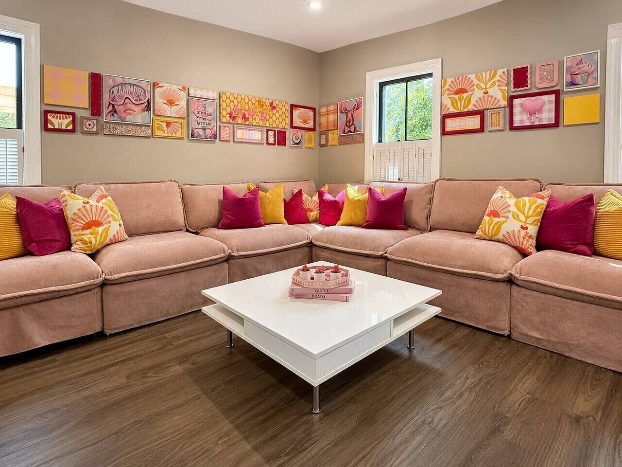 Un salon avec un ensemble de canapés de couleur beige, une table basse blanche et divers tableaux encadrés accrochés aux murs.