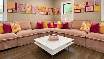 Un salon avec un ensemble de canapés de couleur beige, une table basse blanche et divers tableaux encadrés accrochés aux murs.