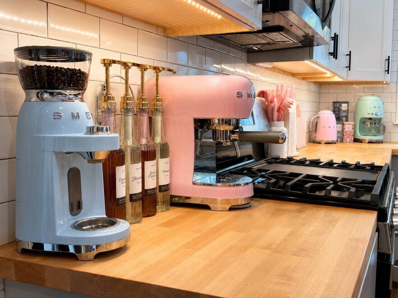 Une cuisine équipée d’une machine à café, d’un appareil à expresso rose et d’une cuisinière.