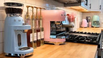 Une cuisine équipée d’une machine à café, d’un appareil à expresso rose et d’une cuisinière.