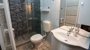Een moderne badkamer met een douchecabine van glas, een toilet en een wastafel met spiegel.