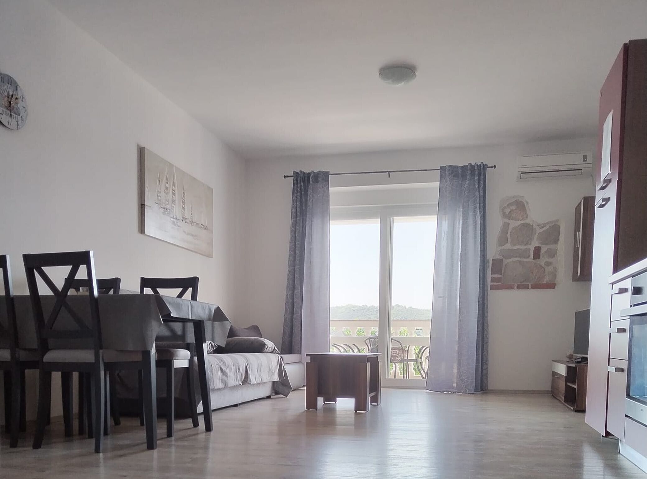 Ein Zimmer mit Esstisch, Stühlen, einer Couch, einem kleinen Tisch und Blick durch eine Glastür.