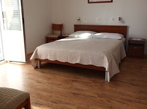 Ein Schlafzimmer mit einem Holzbett, einem Nachttisch, einem Sessel und einem Beistelltisch.