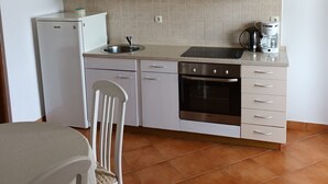 Una cucina compatta con frigorifero, forno, lavello e macchina da caffè.