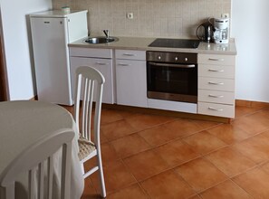Eine kleine Küche mit Kühlschrank, Backofen, Spüle und Kaffeemaschine.