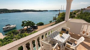 Un balcone con tavolo e sedie che si affaccia su uno specchio d'acqua con barche.