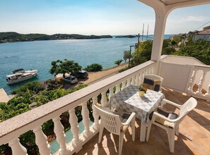 Ein Balkon mit Tisch und Stühlen mit Blick auf ein Gewässer und Boote.