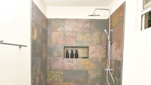 Une salle de bain avec douche, toilettes et une étagère contenant des articles de toilette.