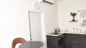 Une cuisine compacte avec un coin repas, une horloge et un climatiseur fixé au mur.