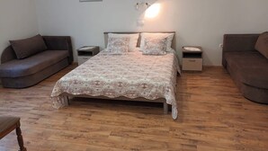 A bedroom with a bed, two nightstands, a sofa, and two wall-mounted lamps. - Superior Two Bedroom Apartment with Sea View and Terrace (Rab)