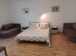 A bedroom with a bed, two nightstands, a sofa, and two wall-mounted lamps. - Superior Two Bedroom Apartment with Sea View and Terrace (Rab)