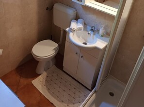 A small bathroom with a toilet, sink, and a shower area. - Superior Two Bedroom Apartment with Sea View and Terrace (Rab)