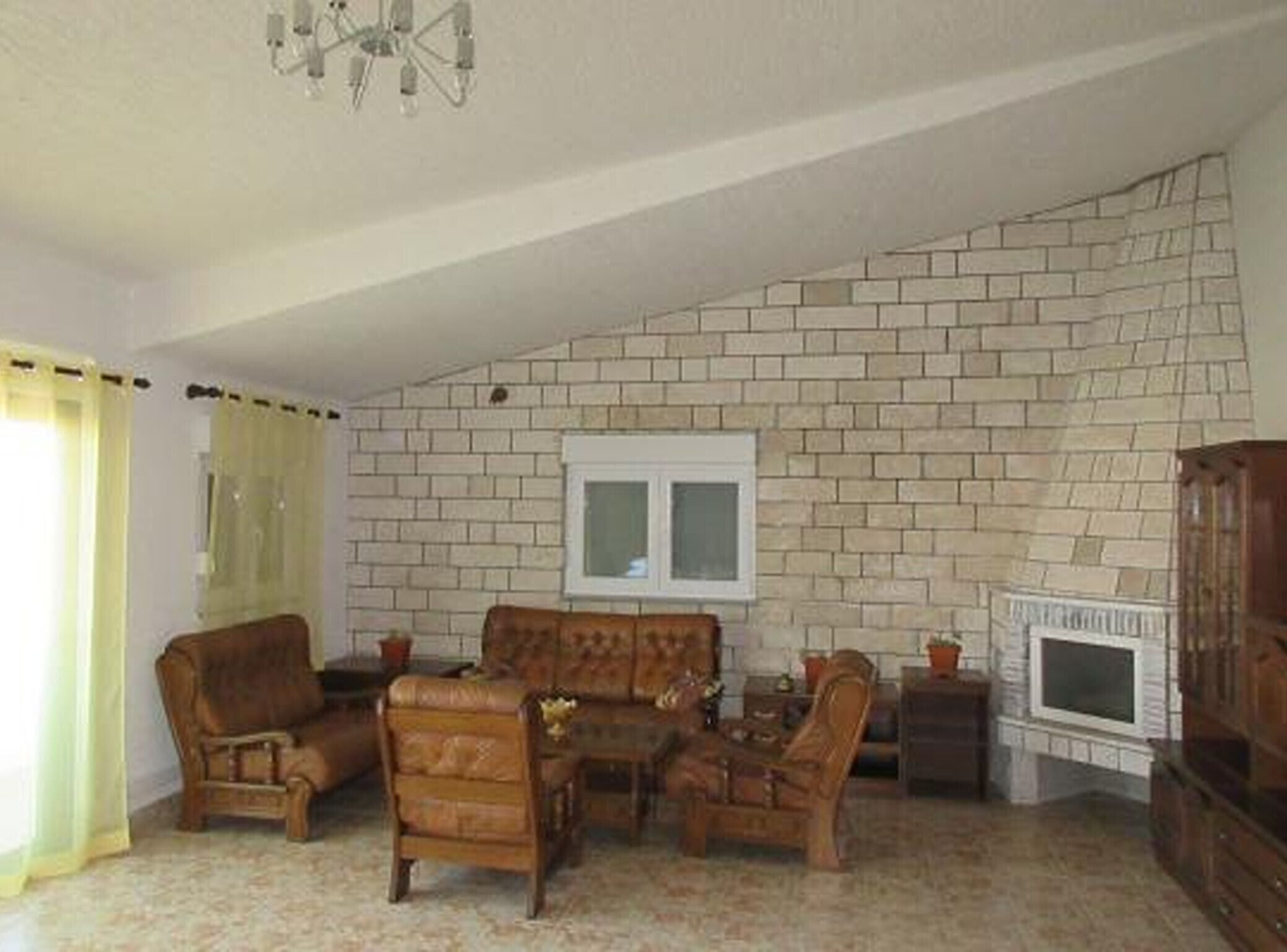 A living room with a brick wall, a television, and wooden furniture.
