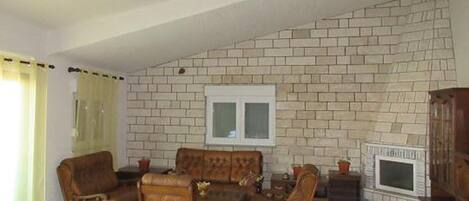 A living room with a brick wall, a television, and wooden furniture.