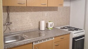A compact kitchen with a sink, stove, and cabinets. - Classic One Bedroom Apartment with Sea View and Balcony (Rogoznica)
