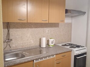 A compact kitchen with a sink, stove, and cabinets. - Classic One Bedroom Apartment with Sea View and Balcony (Rogoznica)