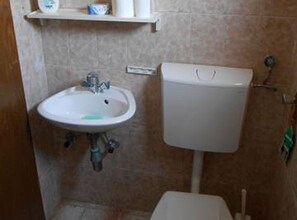 Een badkamer met een wit wastafel, toilet en een toiletrolhouder aan de muur.