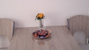 Una mesa de comedor con cuatro sillas, un jarrón con una flor amarilla y un cuenco con diversos objetos.