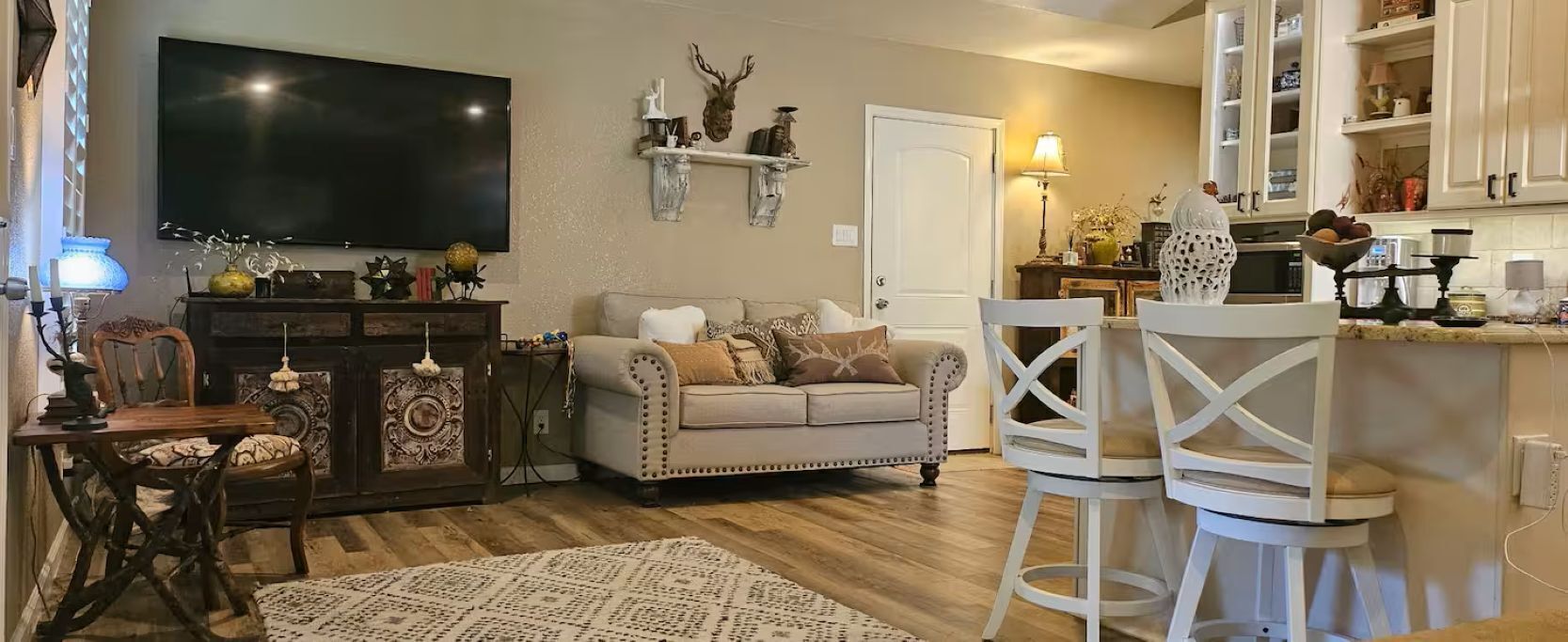 A living room with a sofa, a television, a fireplace, and a kitchen area with cabinets and a countertop.