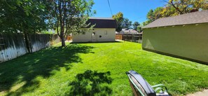 A backyard with a lawn, a wooden fence, and a house with a dark roof. - Old Town Walkable Windsor (Windsor)
