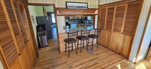 A kitchen with wooden cabinets, a bar area with stools, and a view into the dining room. - Old Town Walkable Windsor (Windsor)