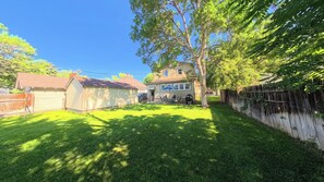 A residential backyard with a lawn, a wooden fence, a shed, and a house with a garage. - Old Town Walkable Windsor (Windsor)