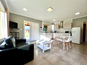 A modern living space with a dining area, kitchen, and a television in the living room.