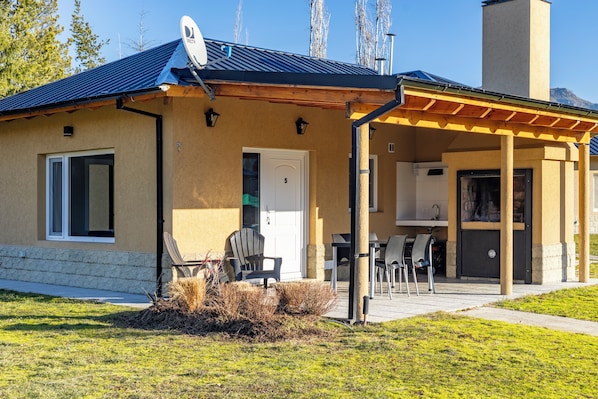 A two-story building with a covered patio area, a satellite dish, and a door marked with the number 5.