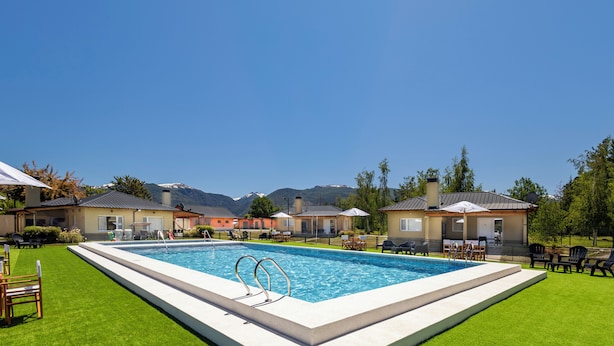 Una piscina con vista sulle montagne sullo sfondo, circondata da case con sedute all'aperto.