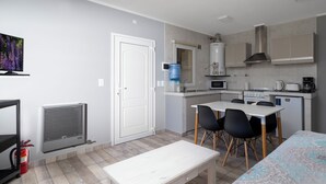 Una cucina compatta con angolo pranzo, dispenser d'acqua, microonde e fornello a gas.