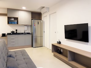 A modern kitchen with a built-in refrigerator, a coffee machine, and a flat-screen TV mounted on the wall.