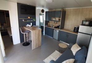Eine kompakte Küche mit Bar, einem Esstisch und einer Couch in einem modernen Wohnraum.