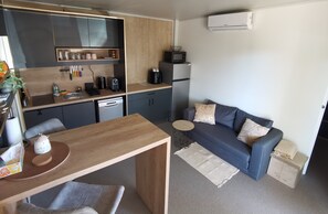 A compact living space with a kitchenette, a dining area, and a seating area with a sofa and cushions. - Excellent 2-bedroom mobile home with AC in charming Sukošan (Sukošan)