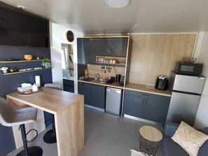 Eine kleine Küche mit einer Holz Arbeitsplatte, einem eingebauten Geschirrspüler und einer Mikrowelle.