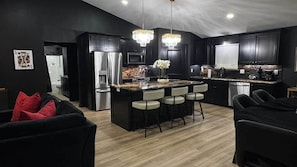A modern kitchen with a central island, bar stools, and a chandelier. - Casino Royale near WinStar - King Suite (Thackerville)
