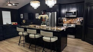 A modern kitchen with a central island, bar stools, a refrigerator, and a microwave. - Casino Royale near WinStar - King Suite (Thackerville)