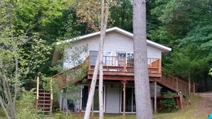 Une maison à deux étages avec une terrasse en bois et un porche couvert.
