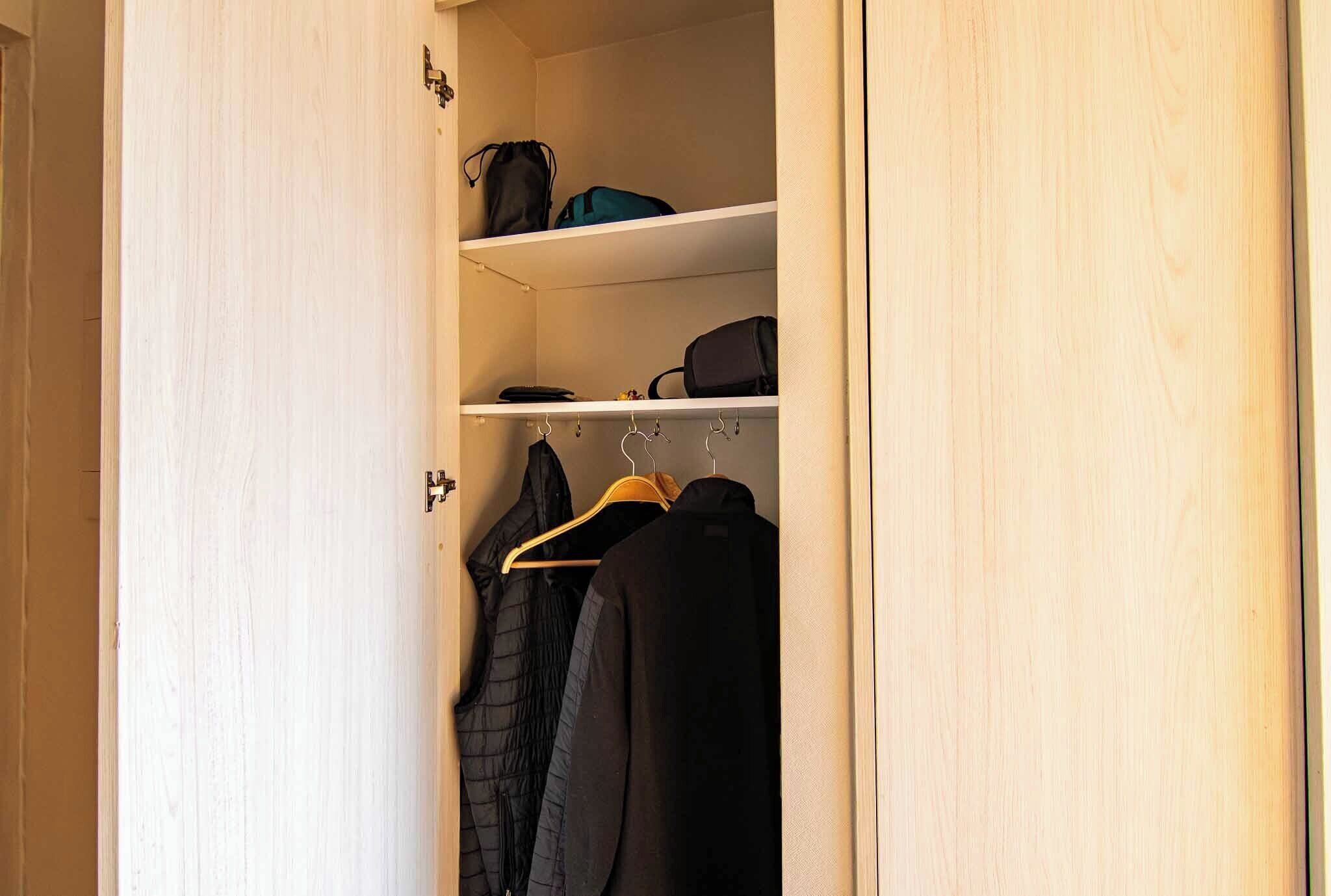 Een kast met kleding en planken met tassen.