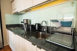 Eine Küche mit Spüle aus Edelstahl, einer Kaffeemaschine, einem Wasserkocher und einem Geschirrtrockner.
