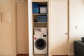 Ein kleiner Hauswirtschaftsraum mit einer Waschmaschine mit Frontlader, Ablageflächen und einer geschlossenen Tür.
