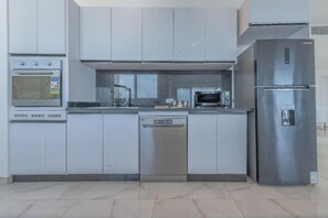 Una cocina moderna con electrodomésticos de acero inoxidable, incluyendo lavavajillas, horno y refrigerador.