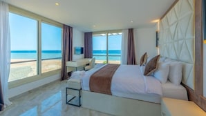 A hotel room with a large bed, a desk, and a view of the beach.